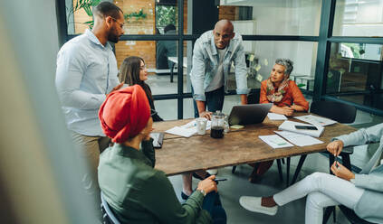 Businesspeople having a group discussion during a meeting in a creative office. Team of multicultural business professionals sharing ideas in an inclusive workplace. - JLPSF11750