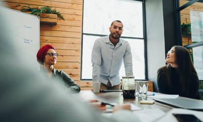 Gruppe von kreativen Geschäftsleuten bei einer Besprechung in einem modernen Büro. Team von multikulturellen Geschäftsleuten beim Brainstorming an einem kreativen Arbeitsplatz. - JLPSF11758