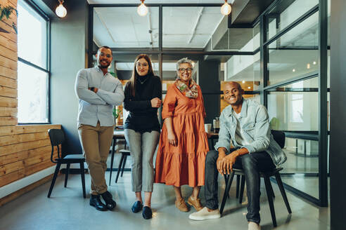 Ein Team erfolgreicher Geschäftsleute lächelt in einem Sitzungssaal in die Kamera. Eine Gruppe multikultureller Geschäftsleute arbeitet an einem modernen Arbeitsplatz zusammen. - JLPSF11780