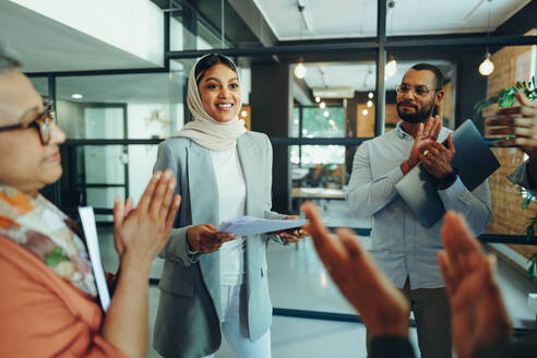 Multikulturelle Geschäftsleute applaudieren ihren Kollegen während einer Besprechung in einem modernen Büro. Eine Gruppe erfolgreicher Unternehmer arbeitet als Team an einem integrativen Arbeitsplatz. - JLPSF11816