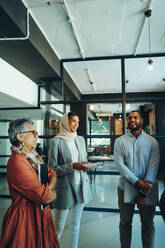 Fröhlich lächelnde Unternehmer während einer Geschäftsbesprechung in einem modernen Büro. Gruppe erfolgreicher Geschäftsleute, die als Team an einem multikulturellen Arbeitsplatz arbeiten. - JLPSF11821