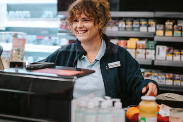 Managerin eines Lebensmittelladens arbeitet an der Kasse. Kassiererin an der Supermarktkasse. - JLPSF11839