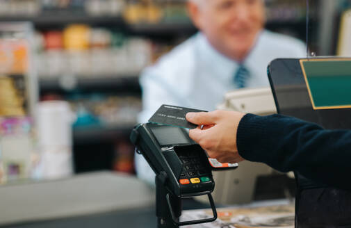 Nahaufnahme eines Kunden, der seine Einkäufe an einer Supermarktkasse bezahlt. Ein Kunde, der mit einer Kreditkarte in einem Geschäft bezahlt. - JLPSF11845