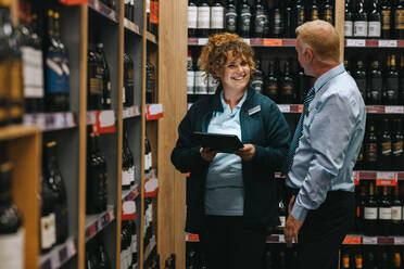 Supermarktleiter im Gespräch mit einem Weinkenner. Zwei Personen, die in einem Weingeschäft arbeiten. - JLPSF11848