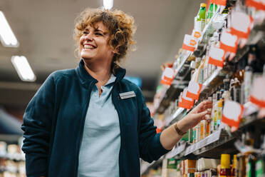 Selbstbewusste Geschäftsfrau, die im Supermarkt an den Regalen steht und lächelt. Weibliche Managerin in einem Lebensmittelgeschäft. - JLPSF11850