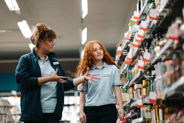 Grocery store manager training new female worker. Grocery store manager explaining work to a new saleswoman. - JLPSF11853