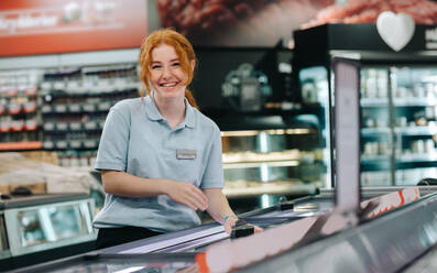 Porträt einer jungen weiblichen Auszubildenden, die in einem Supermarkt arbeitet. Frau bei einem Ferienjob in einem Lebensmittelladen. - JLPSF11859