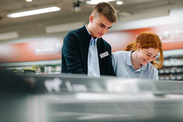 Junge Angestellte eines Lebensmittelgeschäfts arbeiten zusammen. Zwei Supermarktangestellte arbeiten. - JLPSF11869