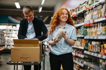 Ein Mann und eine Frau arbeiten in einem Supermarkt und füllen die Regale auf. Angestellte eines Lebensmittelgeschäfts bei der Arbeit. - JLPSF11931