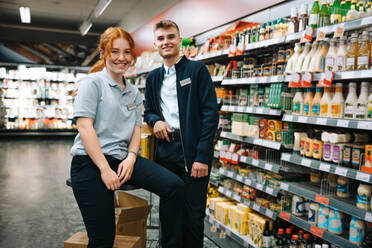 Porträt von zwei Angestellten in einem Supermarkt, die in die Kamera lächeln. - JLPSF11944