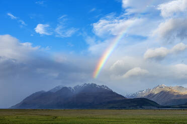 New Zealand, Canterbury Region, Scenic view of rainbow arching over Tasman Valley - RUEF03828