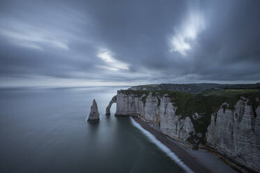 Frankreich, Normandie, Etretat, Klippen von Falaise dAval und Aiguille dEtretat in der bewölkten Abenddämmerung - RUEF03858