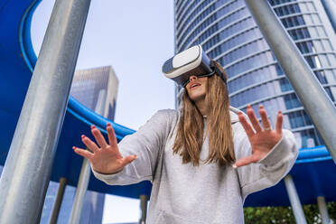 Frau mit Virtual-Reality-Simulator vor einem Gebäude - DLTSF03214