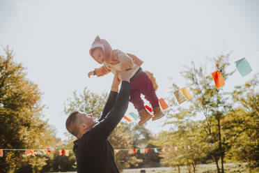 Father picking up boy wearing animal costume on sunny day - MDOF00108