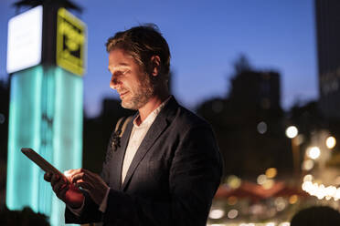 Businessman using smart phone at night - JCCMF07741