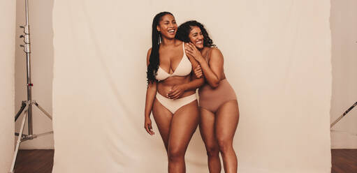Two confident young women kneeling in underwear. Two body positive