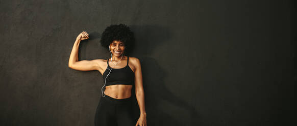 Young woman in a black sports bra and yellow boxing hand wraps proudly  flexes a muscular while posing for a portrait in front of a wooden wall  Stock Photo - Alamy