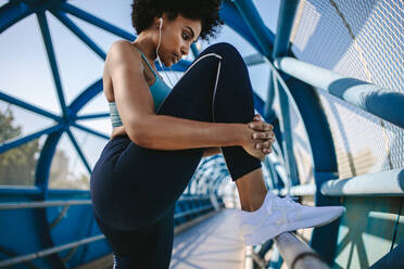 Fitness Frau tun Stretching Training der Beine auf einer Brücke Geländer. Afrikanische Frau tun Training auf einem Gehweg Brücke am Morgen. - JLPSF12370