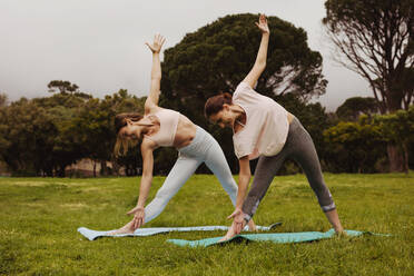 Fitness-Frauen in Dreieckspose beim Yoga in einem Park. Frauen machen Fitness-Workout in einem Park. - JLPSF12416