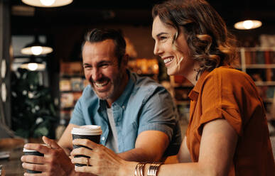 Fröhliches Paar sitzt im Café und trinkt einen Kaffee. Mann und Frau sitzen lächelnd am Tisch im Restaurant und trinken Kaffee. - JLPSF12442