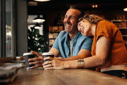 Schöne Frau legt ihren Kopf auf die Schulter eines Mannes, während sie in einem Café sitzt. Lächelndes Paar im Café. - JLPSF12443