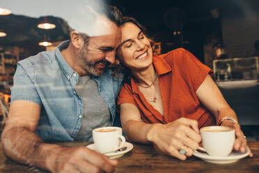 Glückliches Paar sitzt zusammen in einem Café und entspannt sich. Verliebtes Paar trifft sich in einem Café mit Kaffee auf dem Tisch. - JLPSF12450