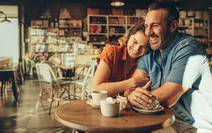 Ein Paar, das in einem Café Zeit miteinander verbringt. Mann und Frau sitzen am Tisch und lächeln. - JLPSF12452