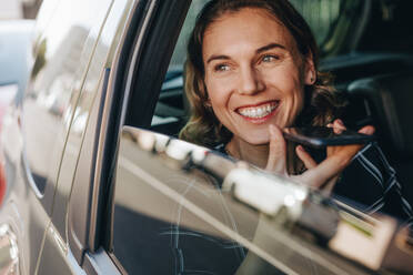 Glückliche Geschäftsfrau, die am Handy spricht, während sie auf dem Rücksitz eines Autos sitzt. Weibliche Geschäftsfrau, die mit einem Auto reist und telefoniert. - JLPSF12464