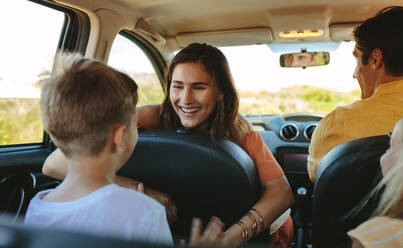 Eine glückliche Familie fährt im Auto, eine Frau spielt mit ihren Kindern auf dem Rücksitz des Autos. - JLPSF12485