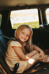 Beautiful girl travelling in backseat of the car. Cute girl in the car looking at camera and smiling. - JLPSF12496