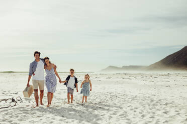 Ehepaar mit ihren Kindern auf dem Weg zum Picknickplatz am Strand. Familie beim Picknick am Strand. - JLPSF12512