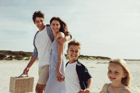 Lächelnder Mann und Frau mit ihren Kindern am Strand für ein Picknick. Glückliche Familie am Strand für Picknick. - JLPSF12513