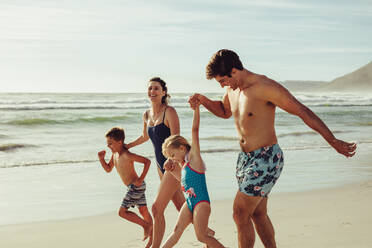 Glückliche Mutter und Vater mit ihren Kindern, die während des Sommerurlaubs am Strand Spaß haben. - JLPSF12524