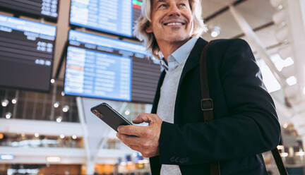 Geschäftsmann mit Mobiltelefon im Flughafenterminal. Internationaler Reisender am Flughafen. - JLPSF12706