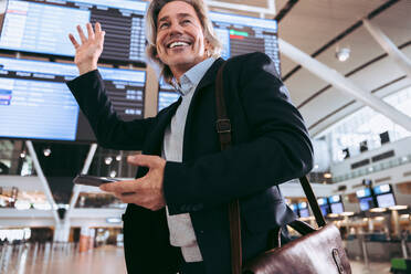 Geschäftsmann winkt auf dem internationalen Flughafen ab. Geschäftsreisender im Flughafen-Terminal. - JLPSF12707