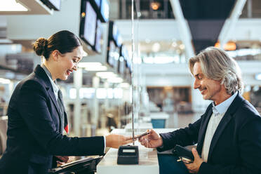 Geschäftsmann reist und macht Check-in am Flughafen. Reisende bekommen Bordkarte für Flug am Flughafen-Terminal. - JLPSF12731