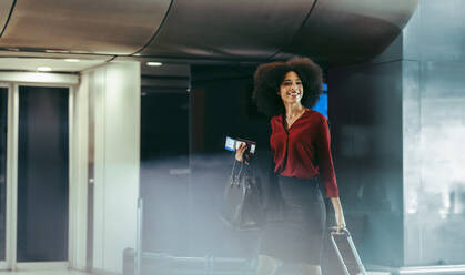 Businesswoman walking in an international airport terminal during transit. Female traveler with bags at airport. - JLPSF12746