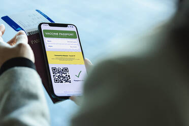 Internationale Reisende mit Covid-19-Impfpass auf ihrem Mobiltelefon. Geimpfte Touristin, die für Reisen während der Coronavirus-Pandemie die digitale e-Passport-App auf ihrem Mobiltelefon nutzt. - JLPSF12768