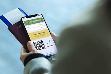 Nahaufnahme einer Touristin am Flughafen mit digitalem Covid-19-Impfpass auf ihrem Handy und Flugticket. Geimpfte Reisende mit digitaler Impfpass-App auf ihrem Handy für Reisen während der Covid-19-Pandemie. - JLPSF12769