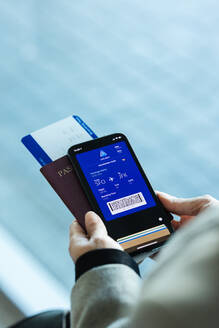 Passagier mit Smartphone, der vor dem Flug die Reiseinformationen auf der elektronischen Bordkarte überprüft. Reisende, die eine digitale Bordkarte für eine Flugreise verwenden. - JLPSF12774