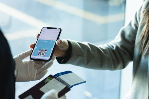 Eine Passagierin zeigt dem Bodenpersonal am Flughafen einen digitalen medizinischen Ausweis auf ihrem Handy. Eine Reisende benutzt das digitale Covid-Schnelltestergebnis als medizinischen Ausweis am Check-in-Schalter für Reisen während der Covid-19-Pandemie. - JLPSF12778