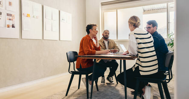Eine Gruppe von kreativen Geschäftsleuten beim Brainstorming in einem modernen Büro. Verschiedene Designer diskutieren während der Arbeit an einem neuen Innenarchitekturprojekt. - JLPSF12788
