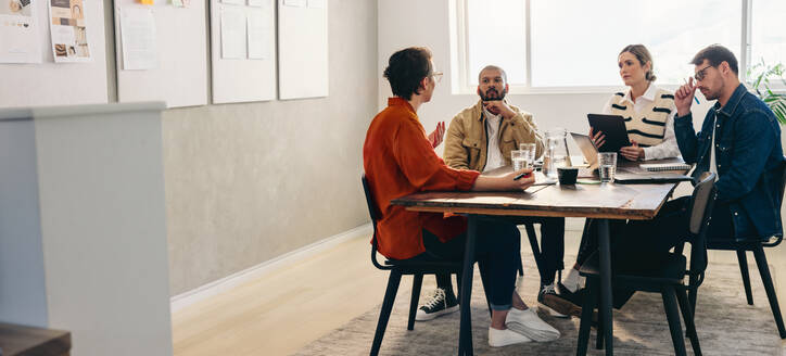 Eine Gruppe von kreativen Geschäftsleuten diskutiert während einer Besprechung in einem Büro. Verschiedene Designer tauschen Ideen aus, während sie gemeinsam an einem neuen Designprojekt arbeiten. - JLPSF12789