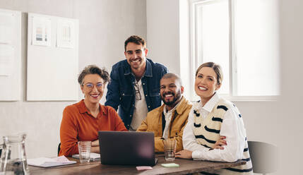 Portrait of successful businesspeople smiling at the camera in a creative office. Group of happy businesspeople working together on a new design project in a modern workplace. - JLPSF12832