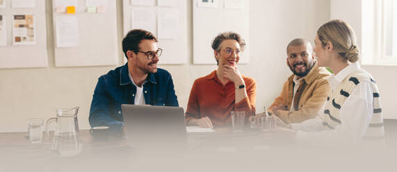 Happy businesspeople smiling while having a meeting in a creative office. Group of cheerful business colleagues sharing ideas while working together on a new interior design project. - JLPSF12847