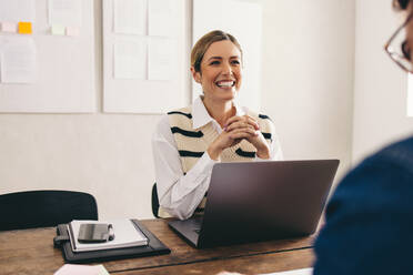 Excited hiring manager smiling cheerfully while interviewing a job candidate in her office. Happy businesswoman having a meeting with a shortlisted applicant. - JLPSF12906