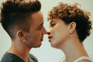 Intimes Paar, das sich küsst. Zärtliches junges queeres Paar, das mit geschlossenen Augen dicht beieinander steht. Junges LGBTQ+ Paar, das einen romantischen Moment im Haus miteinander teilt. - JLPSF12954