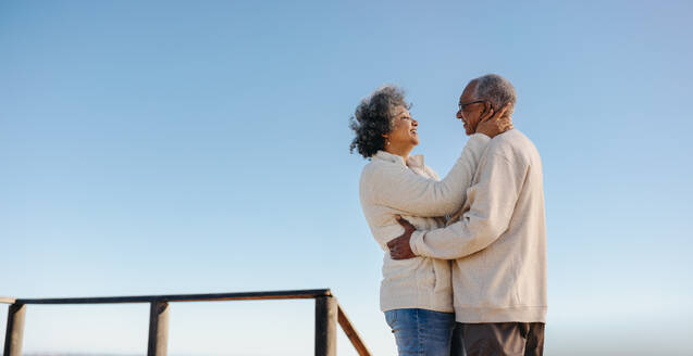 Glückliches älteres Ehepaar, das sich auf der Strandpromenade anlächelt. Romantisches älteres Ehepaar, das nach der Pensionierung viel Zeit miteinander verbringt. - JLPSF12996