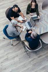 Top view of business team discussing around a table in office. Group of business people having a brainstorming meeting. - JLPSF13051