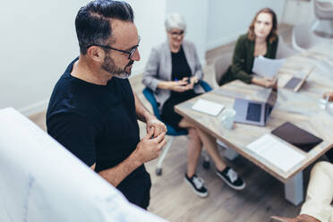 Reifer Geschäftsmann teilt seine Ideen mit Kollegen während einer Präsentation. Männlicher Profi, der seinem Team im Konferenzraum im Büro eine Präsentation gibt. - JLPSF13060